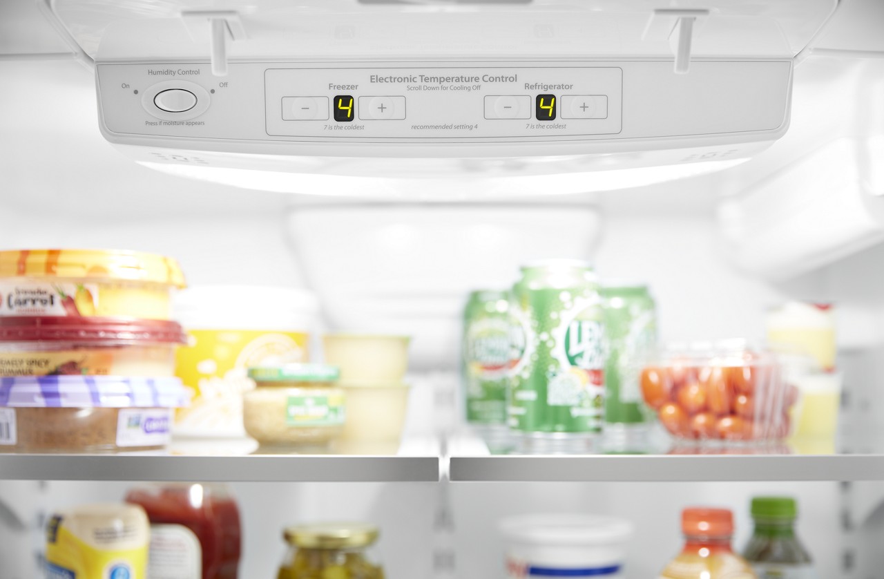 A refrigerator temperature setting gauge with food in the background. A refrigerator temperature setting gauge with food in the background.