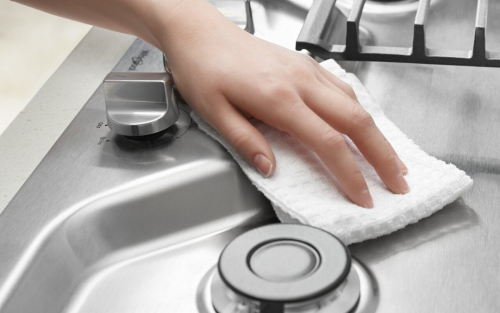 Person cleaning stainless steel cooktop 