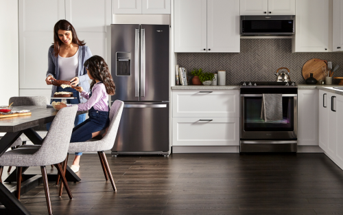 People in a kitchen with stainless steel appliances